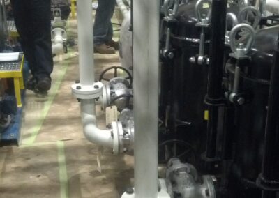 Technicians inspecting industrial piping and valves in a mechanical room, HVAC plant maintenance