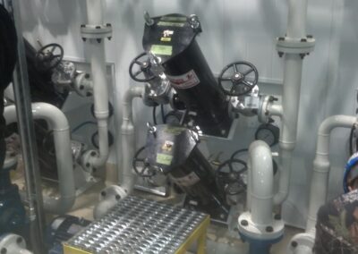 Industrial piping system with valves, gauges and strainers in a mechanical room, technician working.