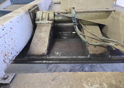 Welded steel frame repair on heavy equipment chassis with reinforcement plates, hydraulic cylinder mount, and wiring.