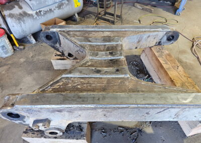 Heavy equipment arm yoke weld repair with new wear plates and bushings in metal fabrication shop