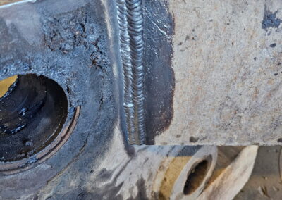 Close-up of clean weld bead on thick steel bracket, industrial metal repair and fabrication in workshop